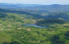 Vista amplia del embalse desde una elevación, mostrando el paisaje rural asturiano