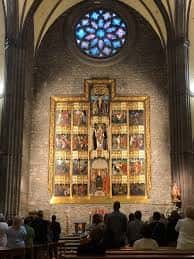 Interior de la iglesia con retablo dorado y rosetón de vitral iluminado