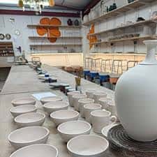 Interior del estudio de cerámica con mesas de trabajo y estanterías llenas de piezas