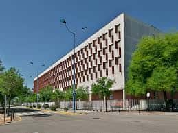 Vista exterior de la Facultad de Comunicación de la Universidad de Sevilla con fachada moderna y árboles alrededor