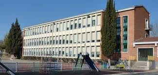 Fachada lateral del colegio con zona de recreo y árboles altos