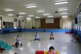 Aula interior con niños jugando en el suelo y material educativo