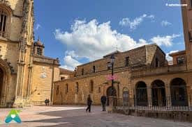Fachada lateral de la iglesia con plaza y cielo azul