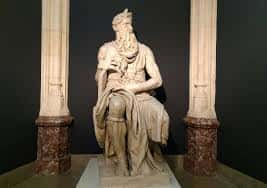 Estatua clásica de un hombre sentado entre dos columnas, en exposición dentro del museo