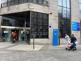 Entrada principal del edificio con personas y señalización institucional