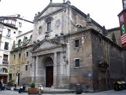 Vista exterior de la Iglesia de los Santos Juanes en Bilbao, mostrando su fachada barroca y entorno urbano