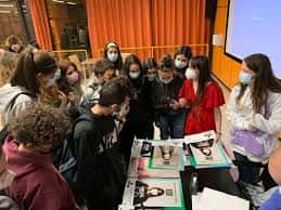 Grupo de estudiantes en un evento dentro de la facultad, con material educativo en mesas