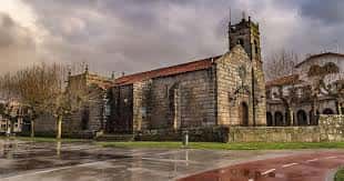 Iglesia de San Miguel de Bouzas en un día nublado, mostrando su estructura histórica y entorno urbano