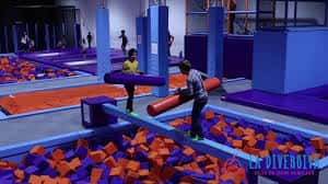 Niños jugando en zona de trampolines con colchonetas de espuma