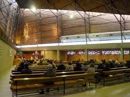 Interior de la iglesia mostrando la nave central y el techo estructural durante una ceremonia