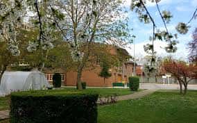 Vista exterior del Colegio Paula Montal Ikastetxea con jardines y árboles en flor