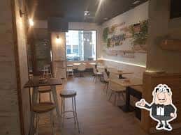 Interior del Bar Malavida con mesas y sillas modernas, iluminación cálida y decoración minimalista