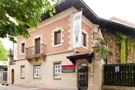 Vista frontal del museo con cartel informativo y entorno arbolado