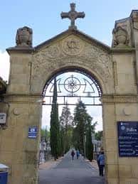 Entrada principal del cementerio con arco de piedra y cruz en la parte superior