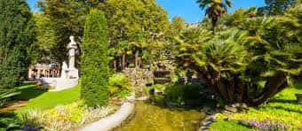 Vista panorámica del jardín con estanque, esculturas y vegetación exuberante