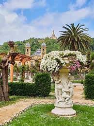 Detalle de una fuente ornamental con flores y palmeras al fondo