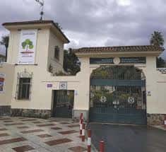 Entrada principal del colegio con portón verde y letrero de Escuelas Católicas