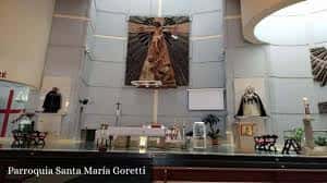 Interior de la parroquia mostrando el altar principal con una gran cruz central y elementos litúrgicos