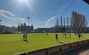 Vista general del campo de fútbol de Tajonar con jugadores en entrenamiento bajo el sol
