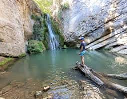 Cascada natural rodeada de rocas y agua cristalina