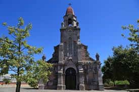 Fachada principal de la iglesia con detalles arquitectónicos y árboles en primer plano