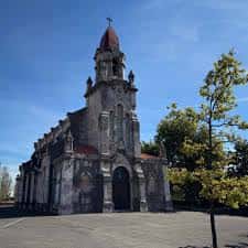 Plaza frontal de la iglesia con vista completa del edificio y cielo azul
