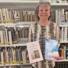 Mujer sosteniendo libros frente a estanterías de la biblioteca