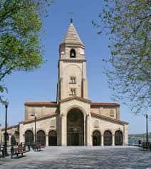 Fachada principal de la iglesia con arcos y campanario bajo luz diurna
