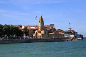 Iglesia de San Pedro vista desde el mar con el puerto y edificios costeros al fondo