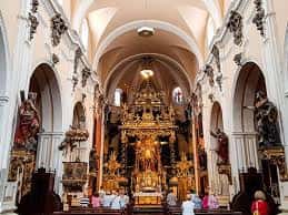 Interior de la iglesia con el altar mayor dorado y congregantes durante una ceremonia