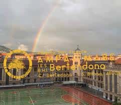 Vista aérea del patio deportivo con arcoíris y fachada del instituto