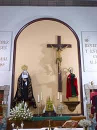 Detalle del altar con crucifijo y vestimentas litúrgicas