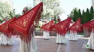 Grupo de danzantes con mantones rojos frente a la iglesia durante una celebración