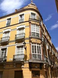 Detalle arquitectónico de un edificio en la Calle Casapalma con balcones forjados y ventanas con marcos blancos