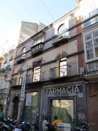Fachada de un edificio en la Calle Casapalma con farmacia en planta baja y balcones de hierro