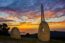 Escultura de granito al atardecer con cielo colorido y paisaje de fondo