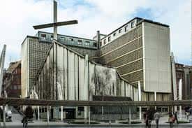 Fachada principal de la iglesia con elementos geométricos y cruz en primer plano