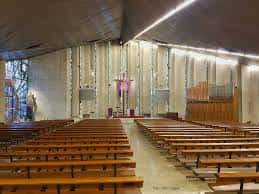 Interior de la iglesia con bancos de madera, altar y iluminación natural
