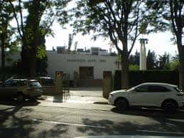 Vista exterior de la Parroquia de Santa Gema con árboles y vehículos estacionados