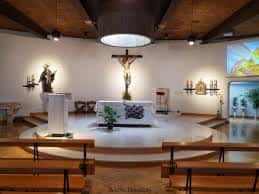 Interior del altar de la Parroquia de Santa Gema con crucifijo y bancos