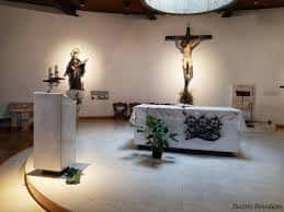 Vista del presbiterio con altar, crucifijo y elementos litúrgicos