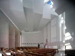 Interior moderno de la iglesia con techos geométricos, luz natural y bancos de madera