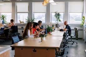 Espacio de coworking en PLATF9RM Brighton con personas trabajando en mesas largas y grandes ventanales