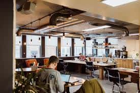 Interior moderno de oficina abierta en PLATF9RM con iluminación industrial y zonas de trabajo compartidas
