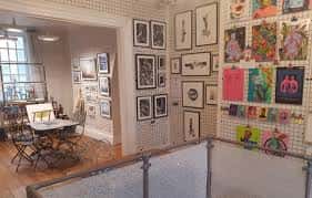 Galería de arte con obras expuestas en paredes de rejilla metálica