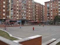 Plaza abierta con personas jugando y edificios de ladrillo en el fondo