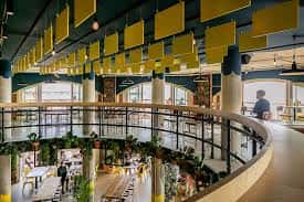 Interior del Shelter Hall con diseño moderno, balcones curvos y paneles acústicos amarillos
