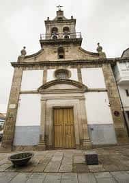 Fachada principal de la Iglesia de Nuestra Señora del Socorro en Ferrol, con puerta de madera y campanario bajo cielo nublado