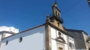 Ángulo elevado de la torre y parte superior de la fachada de la iglesia contra un cielo despejado