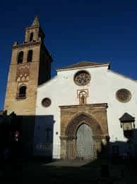 Vista exterior de la Iglesia de Omnium Sanctorum con su torre y fachada blanca bajo cielo azul